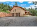 A brick house featuring a two-car garage and an expansive driveway is surrounded by nature at 7815 Armadillo Trl, Evergreen, CO 80439
