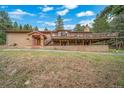 A brick home showcases an expansive deck and inviting front entry amid a verdant landscape at 7815 Armadillo Trl, Evergreen, CO 80439