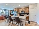 Modern kitchen features a kitchen island with bar stools, wooden cabinetry, and stainless steel appliances at 2475 W 69Th Pl, Denver, CO 80221