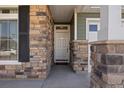 Inviting covered entryway and porch is framed by stone pillars and complementary siding at 5037 N Quemoy St, Aurora, CO 80019