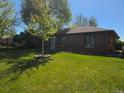 Quaint brick home featuring a lush lawn, newly planted tree and well-maintained landscape at 2285 Ironton St, Aurora, CO 80010