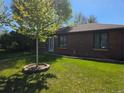 Quaint brick home featuring a lush lawn, newly planted tree and well-maintained landscape at 2285 Ironton St, Aurora, CO 80010