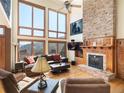 Cozy living room with stone fireplace, high windows with mountain views, and hardwood floors at 76 Raven Ridge Rd, Idaho Springs, CO 80452