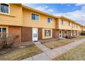 Row of tan brick townhouses with attached garages and a grassy area at 12423 E Louisiana Ave, Aurora, CO 80012