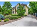 Charming two-story home with lush landscaping and a long driveway, nestled among mature trees for added privacy at 1564 S Uinta Way, Denver, CO 80231