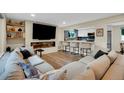 Modern living room featuring an electric fireplace, large TV, hardwood flooring, and an opening to the kitchen at 1260 Hoyt St, Lakewood, CO 80215