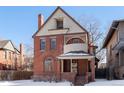 Brick two-story home with a wrap-around porch and snow-covered lawn at 1340 N Gilpin St, Denver, CO 80218