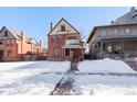 Brick two-story home with a wrap-around porch and snow-covered lawn at 1340 N Gilpin St, Denver, CO 80218