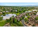 Scenic aerial view showcasing townhomes near a pond, complemented by lush green spaces and distant mountain views at 3240 W 114Th Cir # D, Westminster, CO 80031