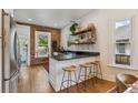 Eat-in kitchen featuring exposed brick wall, counter seating, and hardwood flooring at 2765 W Denver Pl, Denver, CO 80211