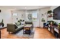 Bright living room featuring hardwood floors, a comfortable green sofa, and large windows at 3775 S Green Ct, Englewood, CO 80110
