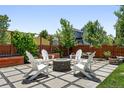 Inviting backyard patio featuring a stone fire pit surrounded by white Adirondack chairs and lush landscaping at 16975 Melody Dr, Broomfield, CO 80023