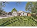 Inviting single-story home featuring a well-kept lawn, mature trees, and a convenient two-car garage at 1367 Teller St, Lakewood, CO 80214