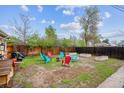 Spacious backyard with a fire pit, colorful seating, garden beds, and mature trees providing shade at 2870 Pontiac St, Denver, CO 80207