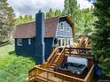 Rear exterior of barn style home showing chimney, hot tub on the deck, and access stairs at 384 Blue Ridge Rd, Breckenridge, CO 80424
