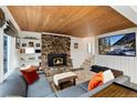 Cozy living room features a stone fireplace, wood ceiling, comfortable seating, and a large TV at 384 Blue Ridge Rd, Breckenridge, CO 80424