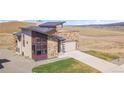 A modern home with stone and siding, a two-car garage, a concrete driveway, and a well-manicured lawn at 5741 Doc Bar Circle, Larkspur, CO 80118