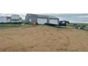 Outbuilding/garage with two rollup doors and a flatbed trailer outside on a large dirt lot at 47904 Dartmouth Ave, Bennett, CO 80102