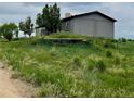 View of the home's exterior showcasing the well-kept lawn and the surrounding natural environment at 47904 Dartmouth Ave, Bennett, CO 80102