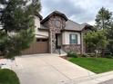 A beautiful home showcasing stone accents, a well-maintained lawn, and a spacious driveway leading to a two-car garage at 6875 Northstar Ct, Castle Rock, CO 80108