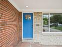 Close-up of a bright blue front door flanked by brick and stone and a view from the window of the outdoor scenery at 9120 W 3Rd Pl, Lakewood, CO 80226