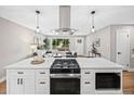 Modern kitchen with a central island featuring a cooktop and pendant lighting with a view of the living room at 9120 W 3Rd Pl, Lakewood, CO 80226