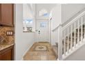 Bright foyer with tile flooring, a staircase, and a front door with transom window at 14023 W Amherst Pl, Lakewood, CO 80228