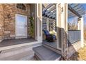 Charming front porch with blue-cushioned chair, stone accents, and a welcoming entrance at 14023 W Amherst Pl, Lakewood, CO 80228