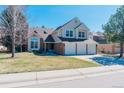 Charming two-story home boasts a 3-car garage, well-manicured lawn, and a classic brick and siding exterior at 7340 Brixham Cir, Castle Pines, CO 80108