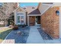 Inviting front entrance with a cozy bench, brick accents, and a beautifully landscaped walkway with rocks at 7340 Brixham Cir, Castle Pines, CO 80108