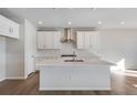Modern kitchen with an island, white cabinets, and a stainless steel range hood at 10022 Wheeling St, Commerce City, CO 80022