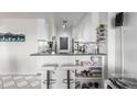 Kitchenette boasts white cabinetry, breakfast bar, and mirrored backsplash at 800 N Washington St # 804, Denver, CO 80203