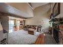 Bright living room with stone fireplace, carpet, and vaulted ceilings at 6625 W 84Th Cir # 48, Arvada, CO 80003