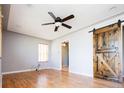 Living room with hardwood floors, ceiling fan, and rustic sliding barn door at 1735 S Wyandot St, Denver, CO 80223