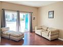 Bright living room with an open door to the outside and comfortable seating and beautiful hardwood floors at 8430 Little Rock Way # 102, Highlands Ranch, CO 80126