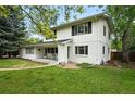 Charming two-story home featuring a brick-and-wood facade and a welcoming front porch, surrounded by lush greenery at 11880 W 30Th Pl, Lakewood, CO 80215