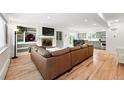 Open-concept living room with a fireplace, built-in shelving, and hardwood floors, flowing into the kitchen area at 11880 W 30Th Pl, Lakewood, CO 80215