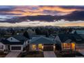 Charming single-Gathering home featuring a well-maintained lawn, attached garage, and picturesque sunset backdrop at 5211 Routt Ct, Arvada, CO 80002