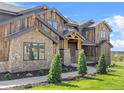 Close up of a rustic home with stone and wood finishes and manicured landscaping at 1587 Arrowpoint Ct, Franktown, CO 80116