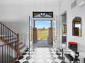 Grand foyer with black and white tiled floor, staircase and view to exterior at 1587 Arrowpoint Ct, Franktown, CO 80116