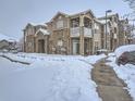 Exterior view of condo building with stone accents and snow-covered walkways showing winter landscape at 7440 S Blackhawk St # 9-108, Englewood, CO 80112