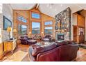 Inviting living room with wood paneling, stone fireplace, large windows showcasing mountain views, and leather seating at 351 Kimmes Ln, Breckenridge, CO 80424