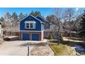 Charming two-story home featuring a brick and blue-sided facade, two-car garage, and mature landscaping at 7464 Shoreham Pl, Castle Pines, CO 80108