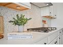 Close-up of modern kitchen with white cabinets, stylish backsplash, and cooktop at 5078 S Quail St, Littleton, CO 80127
