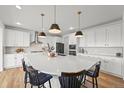Bright kitchen with a large center island, pendant lighting, and white cabinetry at 5078 S Quail St, Littleton, CO 80127