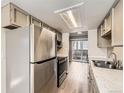 Kitchen features stainless steel appliances, white marble counter tops, and light wood floor at 8717 Carr Loop, Arvada, CO 80005