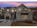 Two-story house with gray siding, stone accents, and solar panels at dusk at 10993 Ledges Rd, Parker, CO 80134