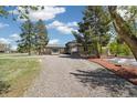 Charming tan home with stone details, large gravel driveway, and mature shade trees at 1866 Mountain View St, Erie, CO 80516