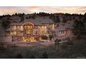 Rear exterior view of beautiful home on a hill, featuring a large patio, stone accents and lots of windows at 10177 Rancho Montecito Dr, Parker, CO 80138