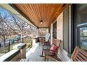 Inviting covered front porch with comfortable seating, perfect for relaxing and enjoying the outdoors with wood ceiling and accents at 438 S Emerson St, Denver, CO 80209